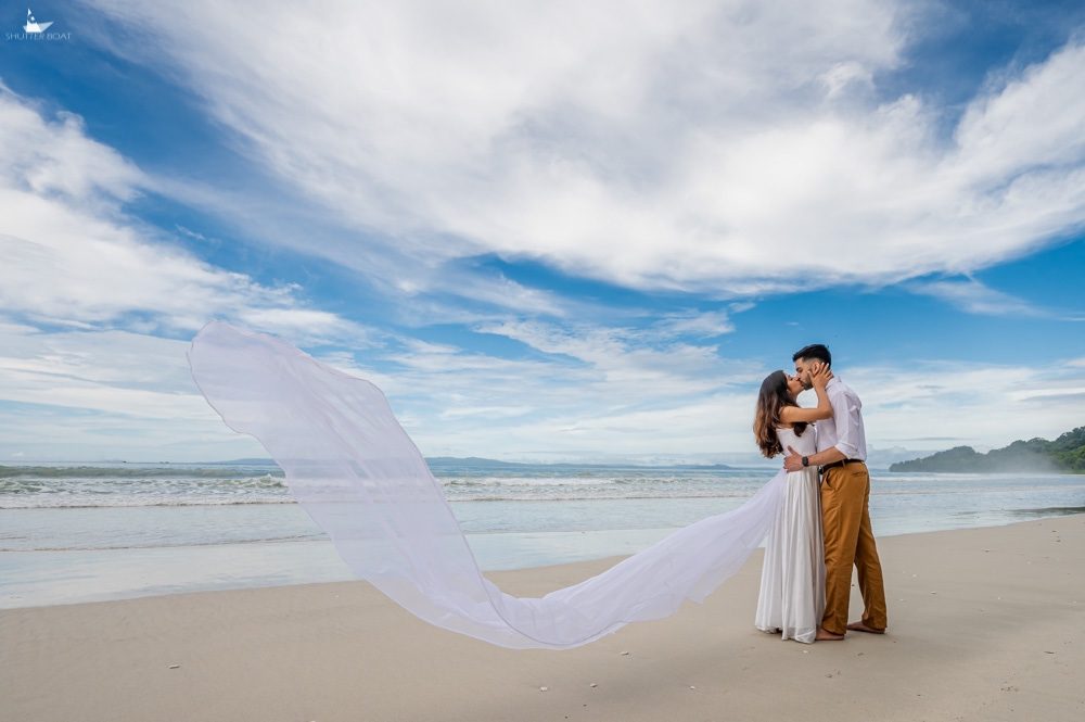 Couple on the beach with a long flowing white veil
